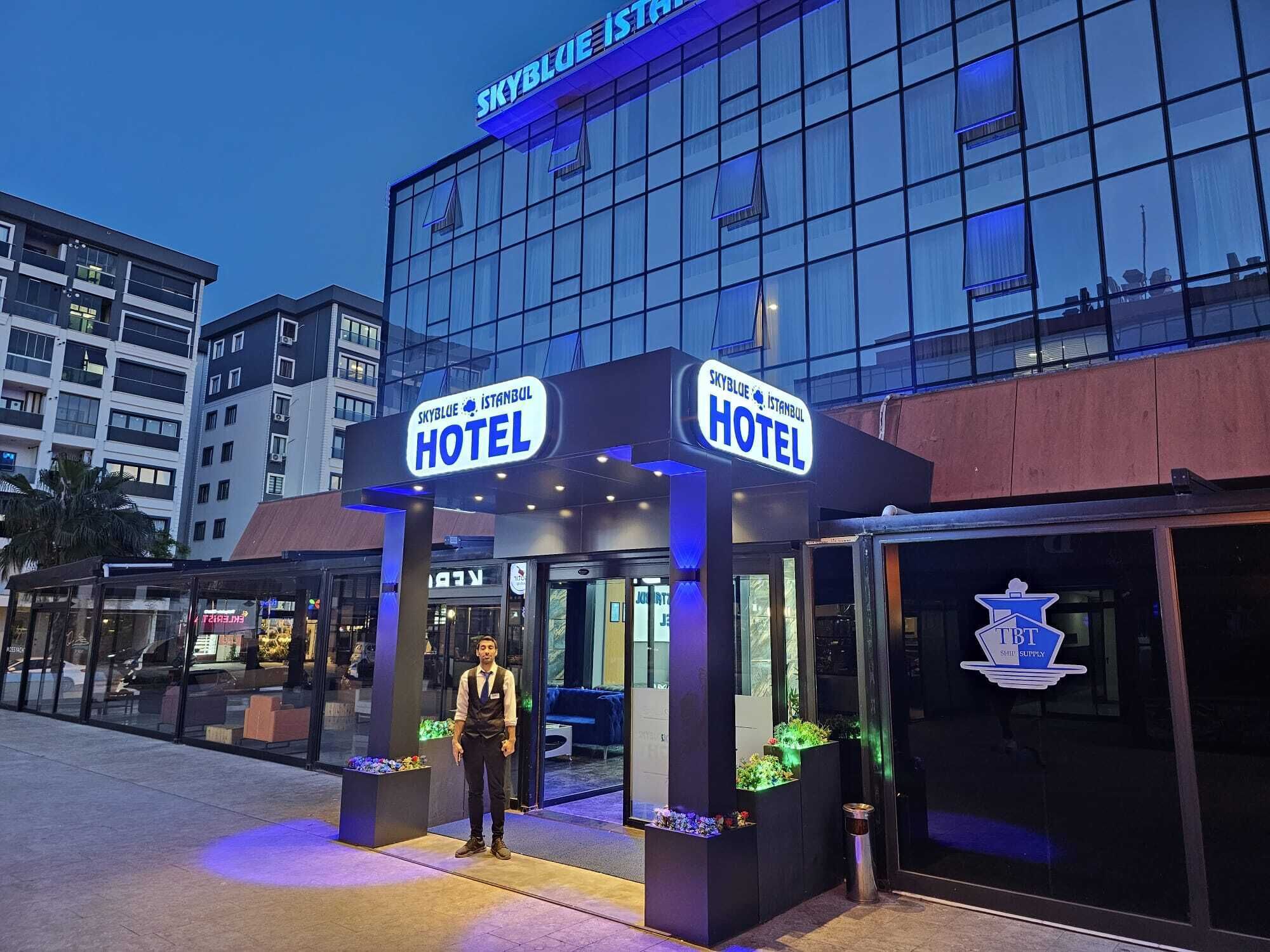 Exterior de l'Hotel SkyBlue Istanbul, amb façana de vidre moderna i senyalització il·luminada.