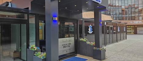 Exterior del Hotel SkyBlue Istanbul, con un diseño moderno, que presenta amplios ventanales y una alfombra azul que conduce a la entrada.