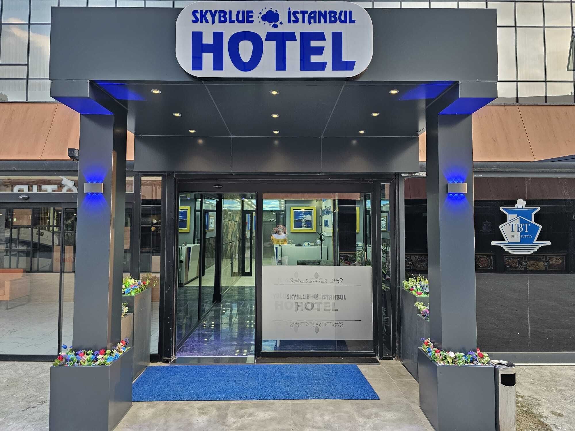 Der Eingang zum Skyblue Istanbul Hotel mit blauem Teppich und Blumenschmuck.