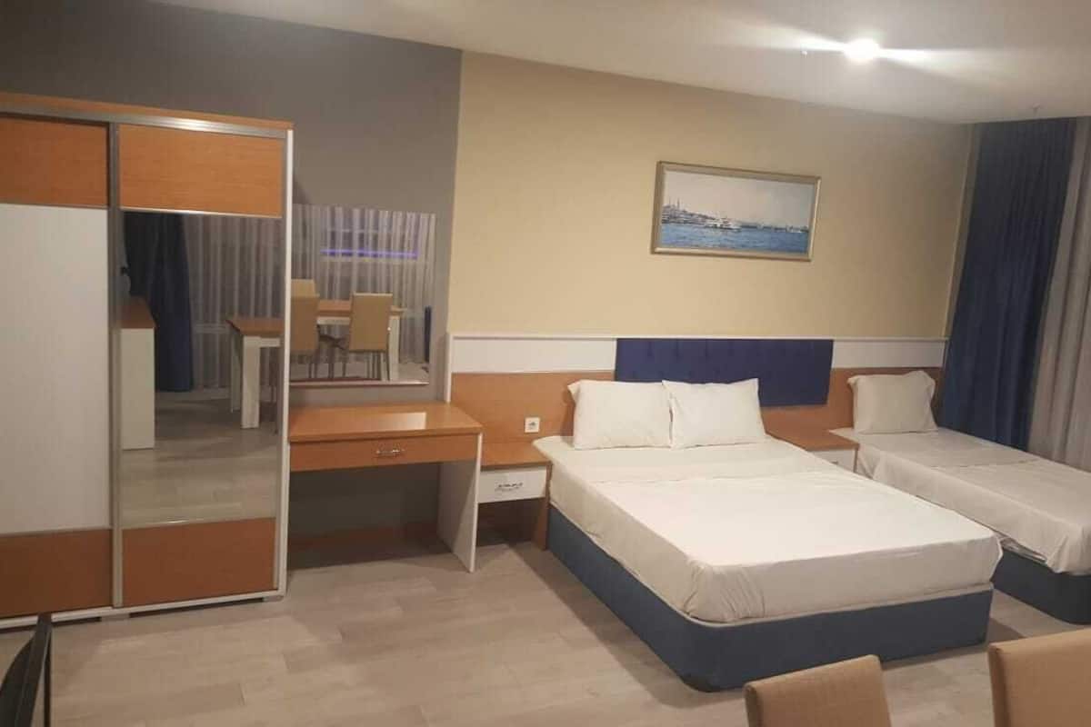 Une chambre d’hôtel avec deux lits, un bureau, une chaise, un miroir et un tableau au mur.