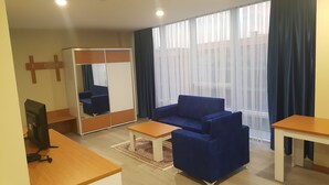 Una habitación moderna con un sofá azul, una mesa de centro de madera, un televisor y un espejo grande.
