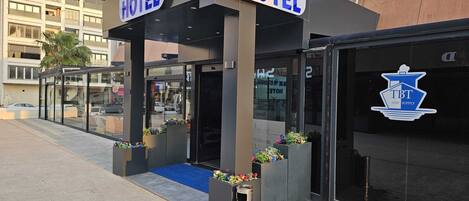 A hotel entrance with a glass canopy, signage for 'Skyblue Istanbul Hotel', and a 'TBT Ship Supply' logo.