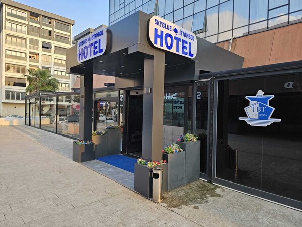 A hotel entrance with a glass canopy, signage for 'Skyblue Istanbul Hotel', and a 'TBT Ship Supply' logo. - Skyblue Istanbul Hotel (Tuzla)
