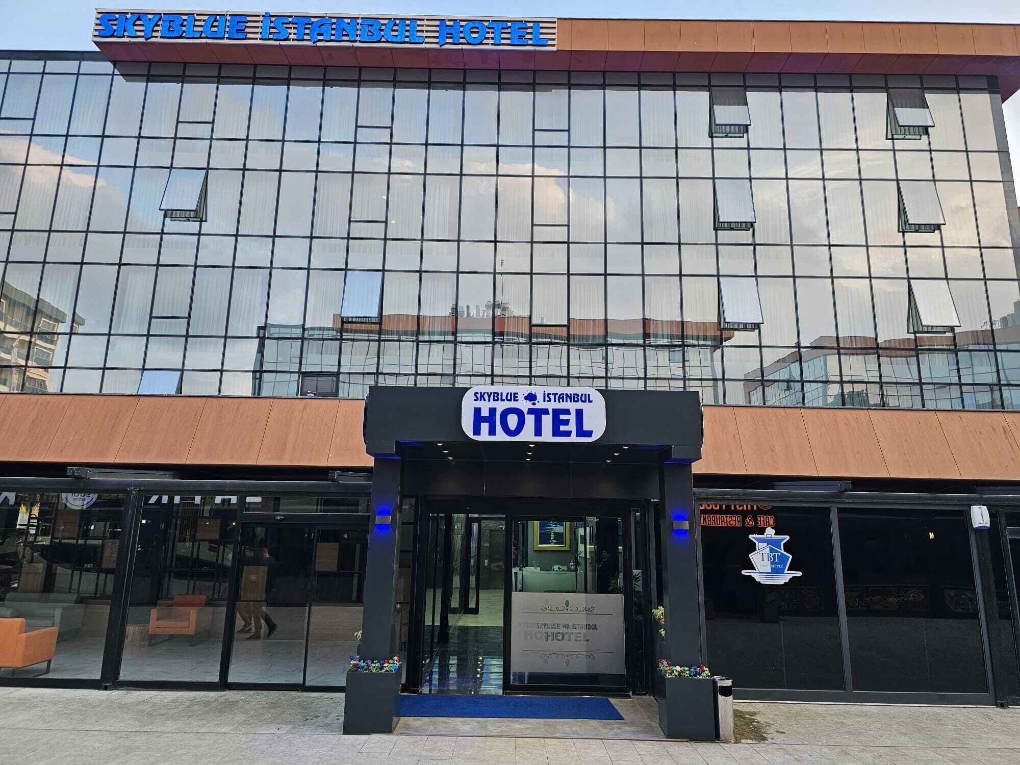 Een modern hotel met een glazen gevel en een opvallend bord waarop 'Skyblue Istanbul Hotel' staat.