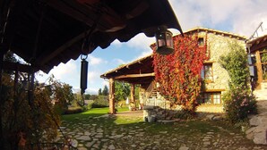 A stone building with a covered porch and a hanging lantern. - Casa rural cal Rei (Lles)