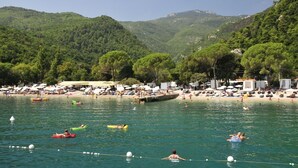 A beach with people swimming and sunbathing, surrounded by lush green hills. - Apartment in Opatija with Seaview, Balcony, Air condition, WIFI (4812-2) (Opatija)