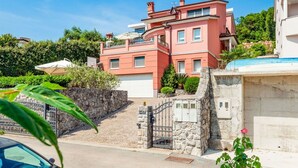 A multi-story residential building with a stone wall and gate, surrounded by greenery. - Apartment in Opatija with Seaview, Balcony, Air condition, WIFI (4812-2) (Opatija)