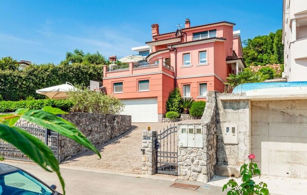 A multi-story residential building with a stone wall and gate, surrounded by greenery. - Apartment in Opatija with Seaview, Balcony, Air condition, WIFI (4812-2) (Opatija)