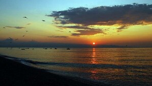 A sunset over a calm sea with boats and birds. - Villa near Taormina. (Furci Siculo)