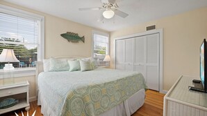Une chambre à coucher comprenant un lit, un ventilateur de plafond, un décor sur le thème des poissons, une armoire et un téléviseur.
