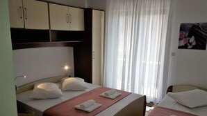 Une chambre d’hôtel avec deux lits, une armoire et une fenêtre avec des rideaux.