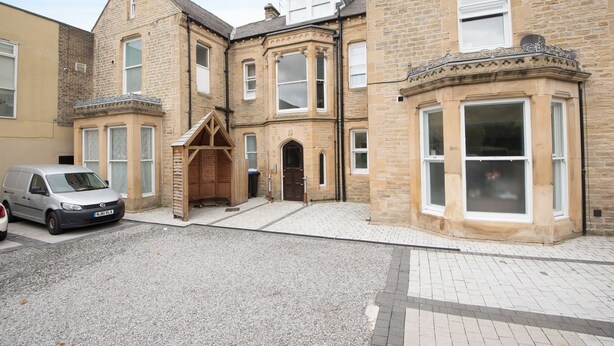 A corner building with a stone facade, large windows, and a wooden entrance. - 80 Kingsway (Bishop Auckland)