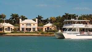 Een groot huis met zwembad en een boot genaamd 'DOUBLE SUNSHINE' in het water.