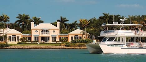 A waterfront property with a large house and a boat named 'DOUBLE SUNSHINE' docked.