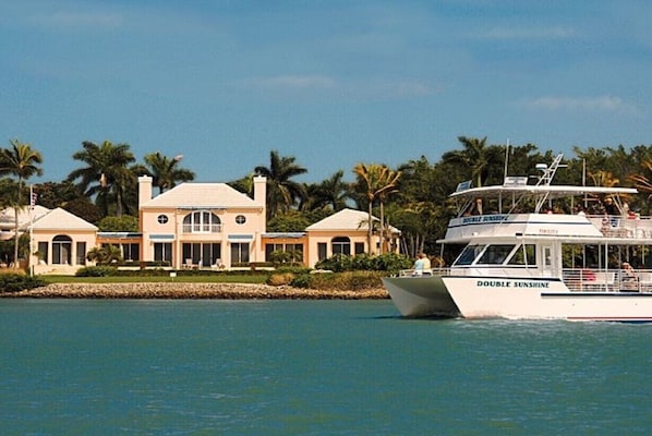 Ein großes Haus mit Schwimmbad und einem Boot namens "DOUBLE SUNSHINE" im Wasser.