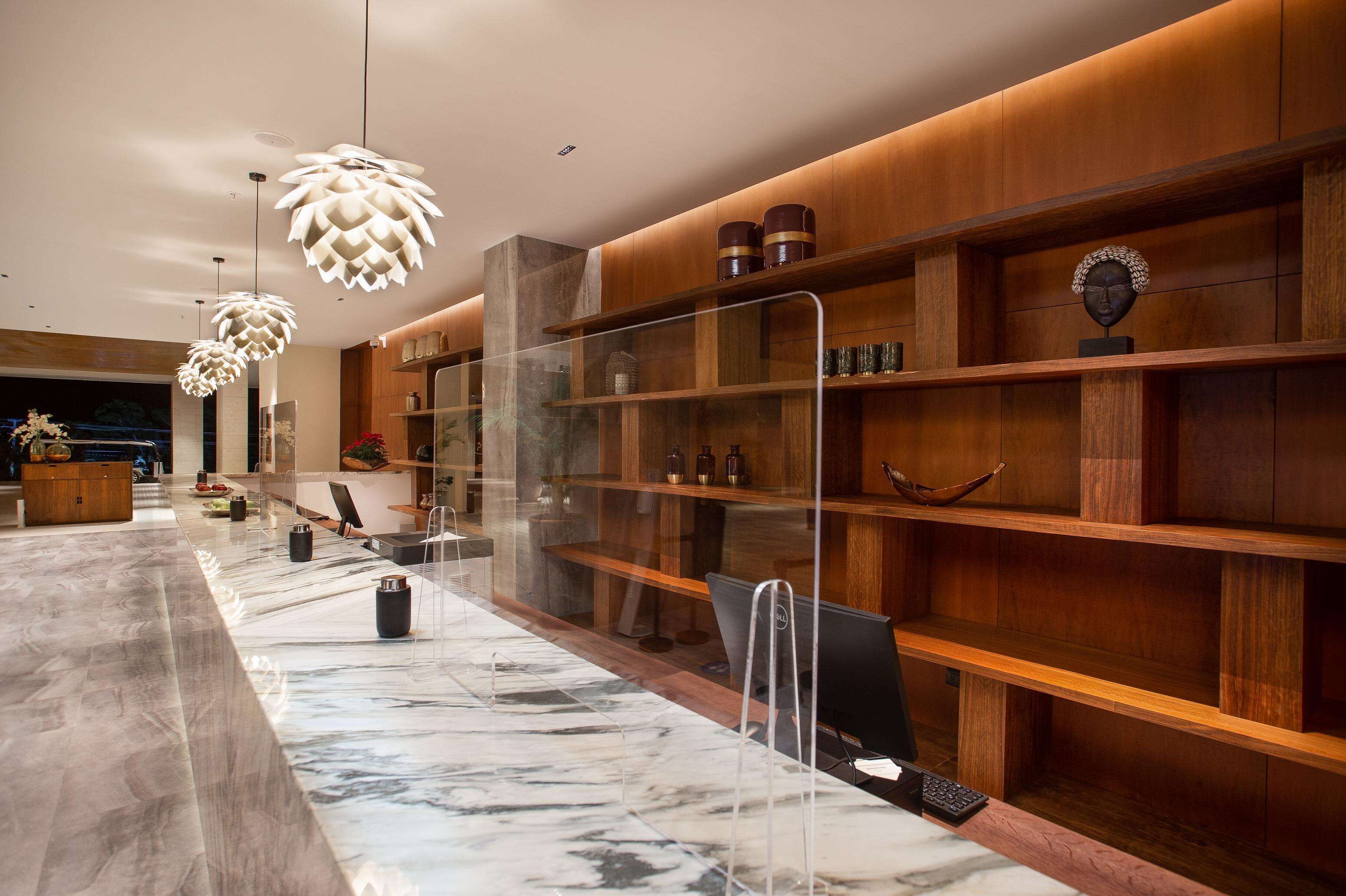 Una zona de recepción moderna con mostradores de mármol, estanterías de madera e iluminación colgante original.