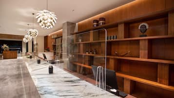 Una zona de recepción moderna con mostradores de mármol, estanterías de madera e iluminación colgante original.