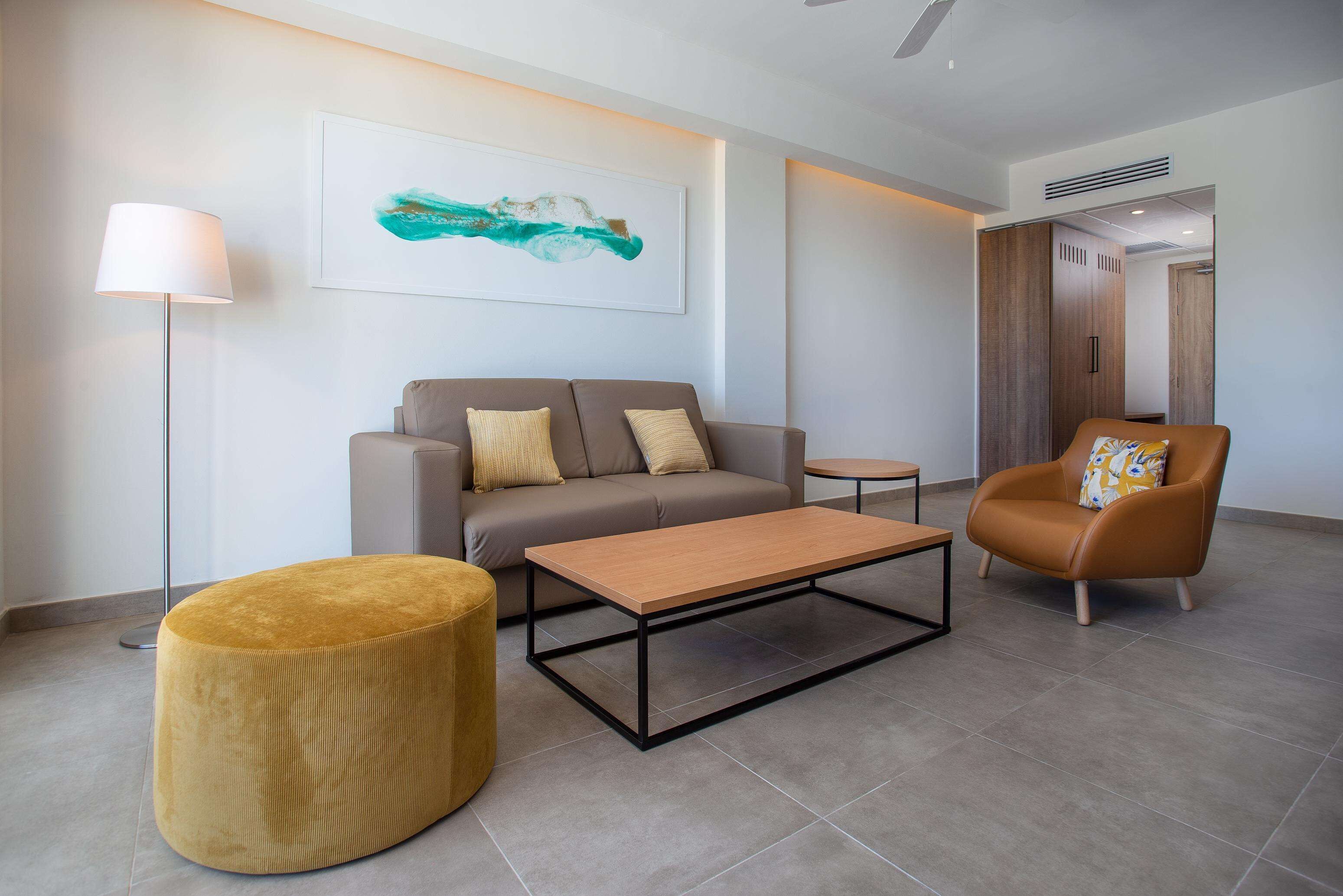 A modern living room with a sofa, armchair, ottoman, and coffee table.