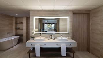 A modern bathroom with two sinks, a large mirror, and a freestanding bathtub.