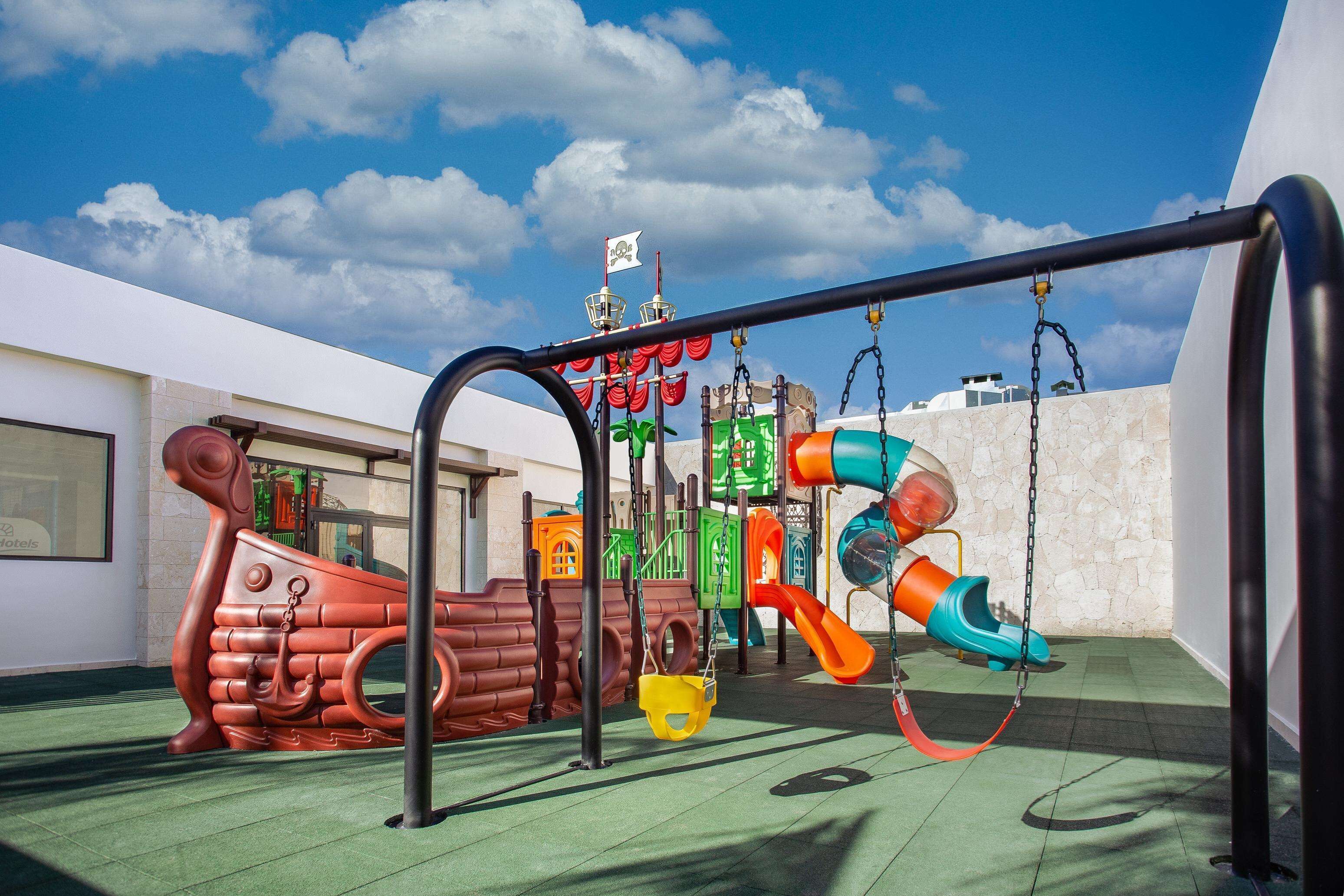 A children's play area with a slide, swings, and a ship-themed play structure.