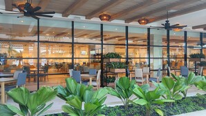 A modern hotel lobby with glass partitions, indoor plants, and a Buffet restaurant sign. - Serenade Punta Cana Beach & Spa Resort - All Inclusive (Punta Cana)