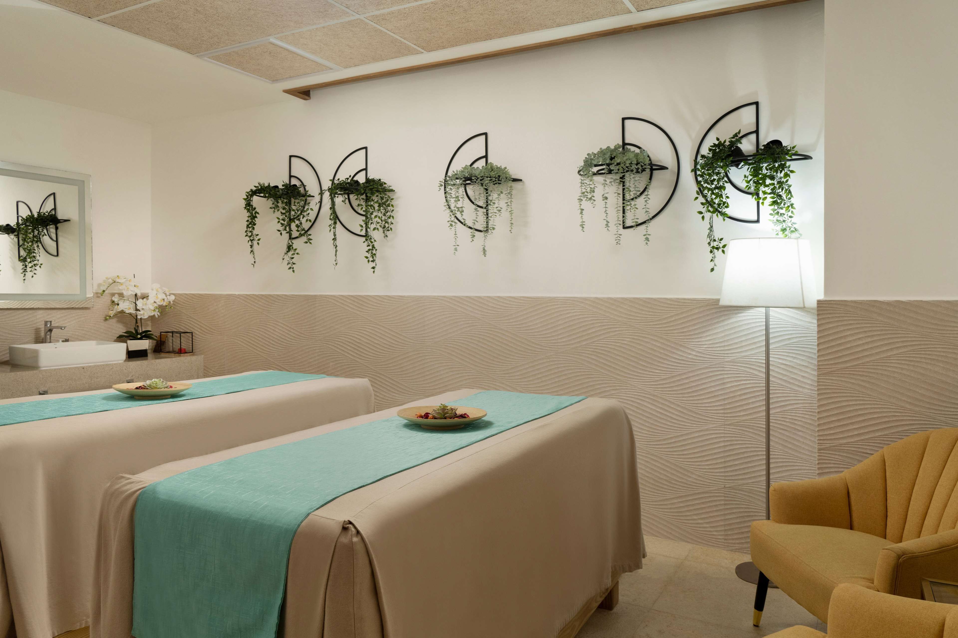Una stanza spa con due lettini per massaggi, un lavandino e fioriere a parete.