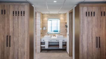 A modern bathroom with wooden cabinets, a double sink vanity, and a large mirror.