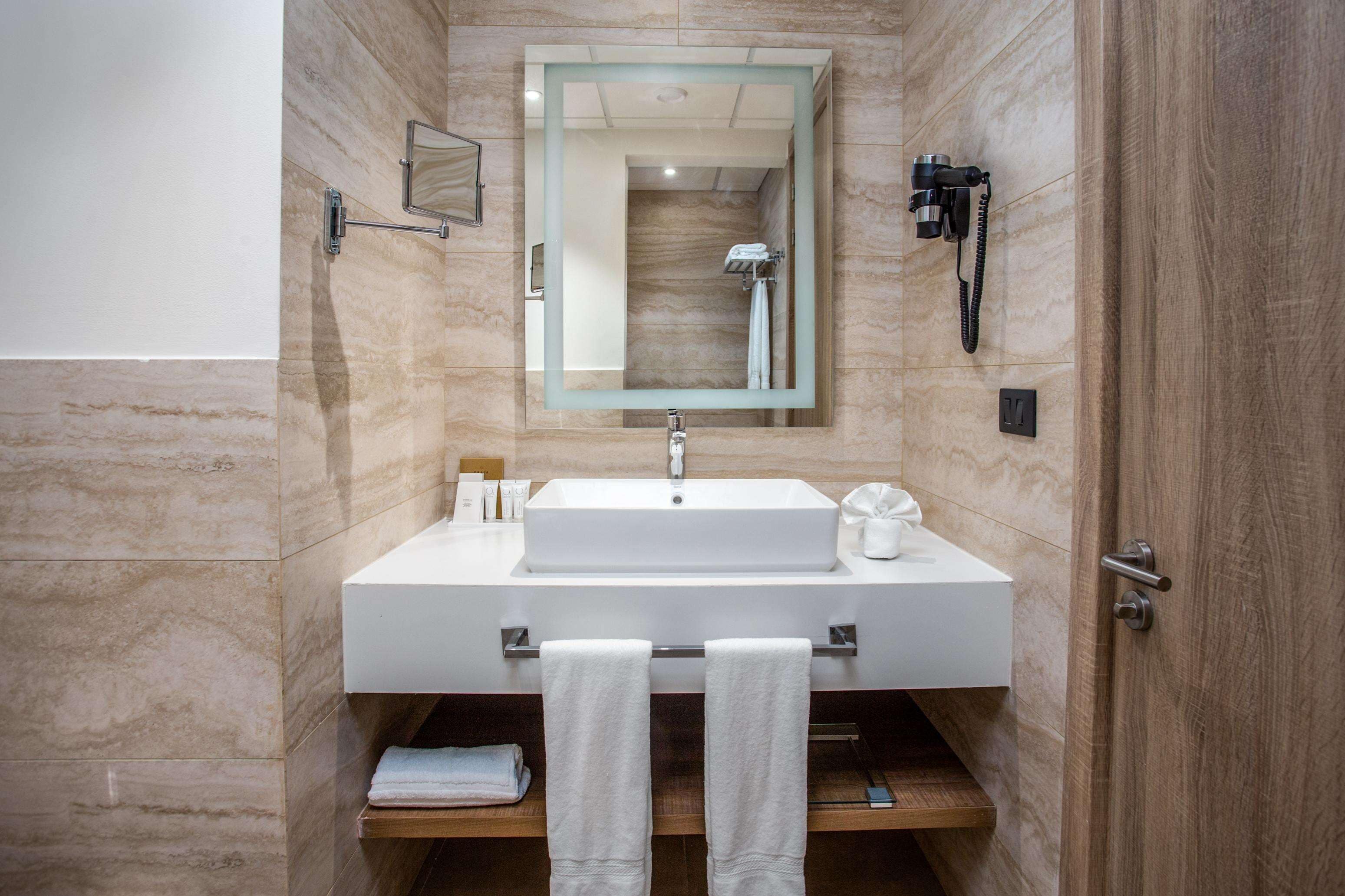A modern bathroom with a large mirror, a sink, and a shower.