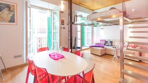 Una sala de estar moderna con una mesa blanca y sillas rojas, un sofá y una cama litera.