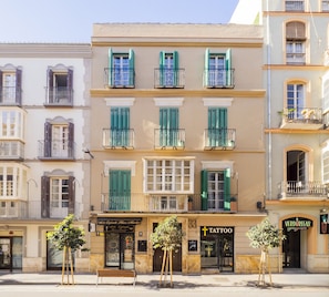 A building with multiple balconies, a storefront with a tattoo shop, and a bench in front.