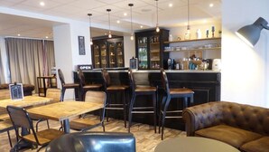 A modern lounge area with leather seating, a bar, and a coffee station.