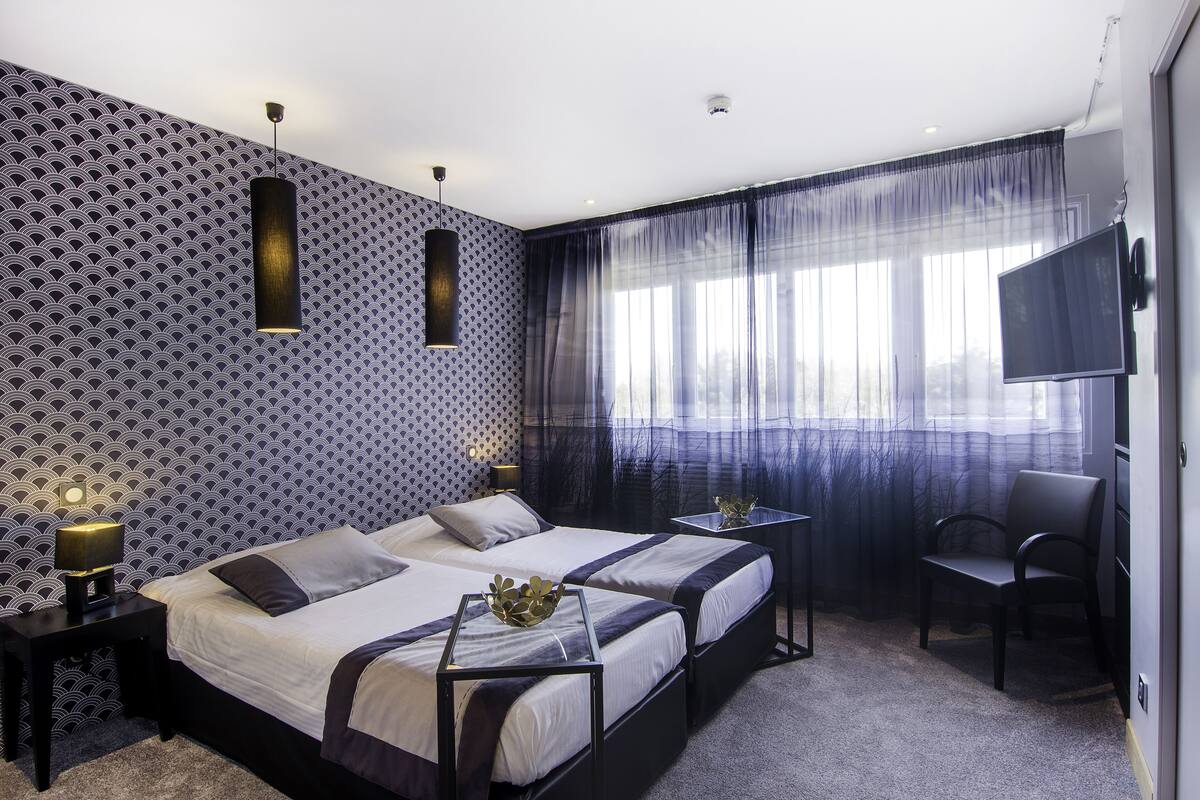Une chambre d’hôtel avec deux lits, une télévision, un bureau et une chaise.