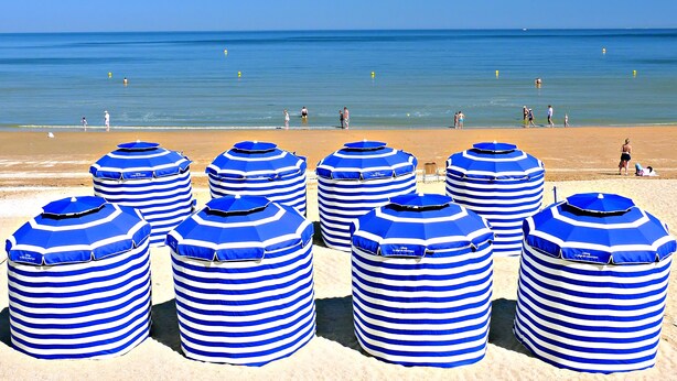 A beach with striped beach umbrellas and beach chairs.