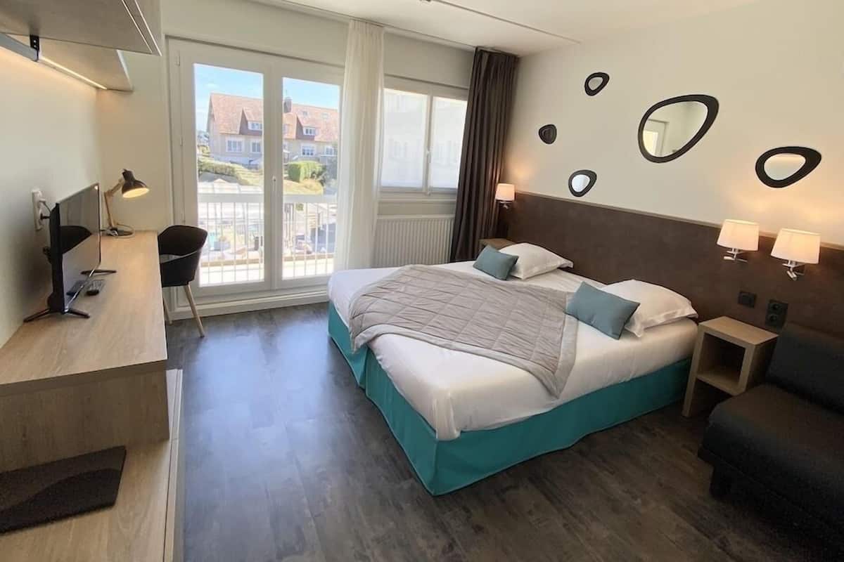 Une chambre d’hôtel équipée d’un lit, d’un bureau, d’une chaise et offrant une vue sur l’extérieur.
