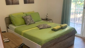 A bedroom with a bed, bedside table, and a window with curtains.