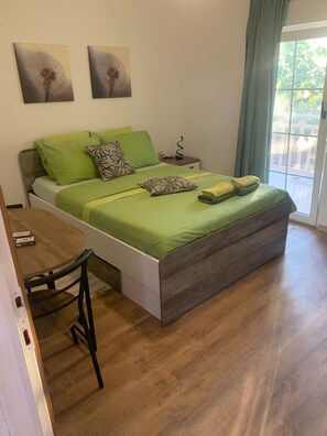 A bedroom with a bed, a bedside table, a chair, and a window with curtains.