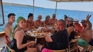 A group of people dining on a boat with a view of the sea.