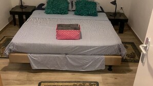 A bedroom with a bed, two nightstands, a painting, and a rug.