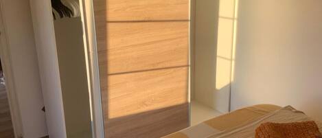 A bedroom with a bed, a wardrobe, and a mirror.