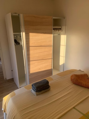 Ein Schlafzimmer mit Bett, Kleiderschrank und Spiegel.