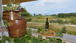 A rustic outdoor setting with a wooden barrel, a bottle of wine, and a bowl of grapes on a balcony overlooking a scenic landscape. - Apartment in Vrsi with Balcony, Air condition, WIFI (4824-5) (Vrsi)