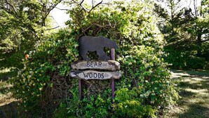 Un letrero de madera con la silueta de un oso y las palabras 'BEAR WOODS', que indica un área natural.