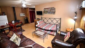 Una sala de estar acogedora con un sofá, una mesa de centro, un televisor y un televisor montado en la pared.