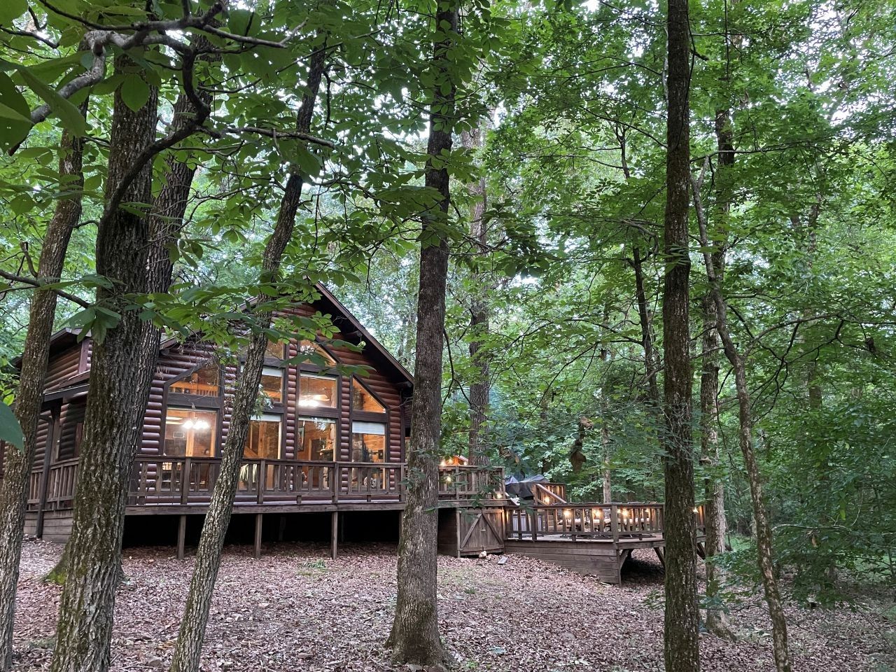 Een vakantiehuisje met een terras en grote ramen, omgeven door bomen.