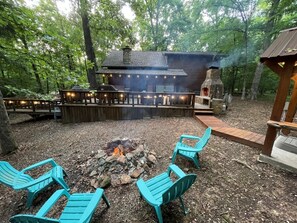 Un espace extérieur aménagé avec des sièges, un foyer, des fauteuils Adirondack et une cheminée en pierre.