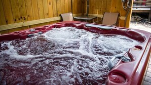 Een hottub in een terras van hout, met een tafel en stoelen in de buurt.