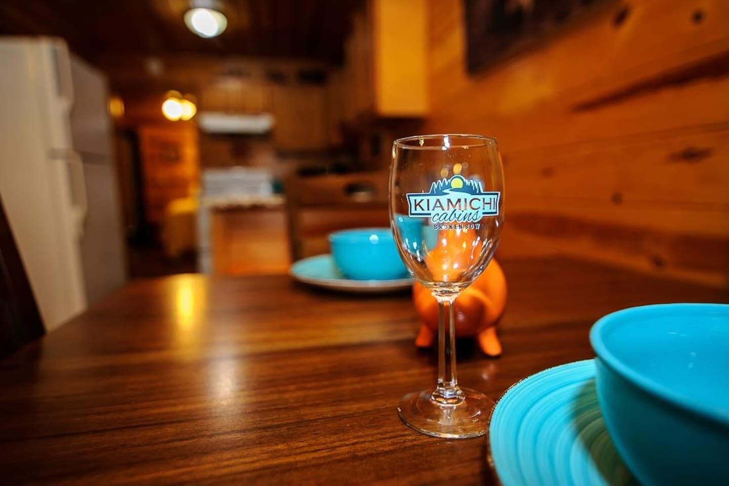 Een houten tafel met een glas met de tekst 'Kiamichi cabins Brokenbow' en een spaarvarken.
