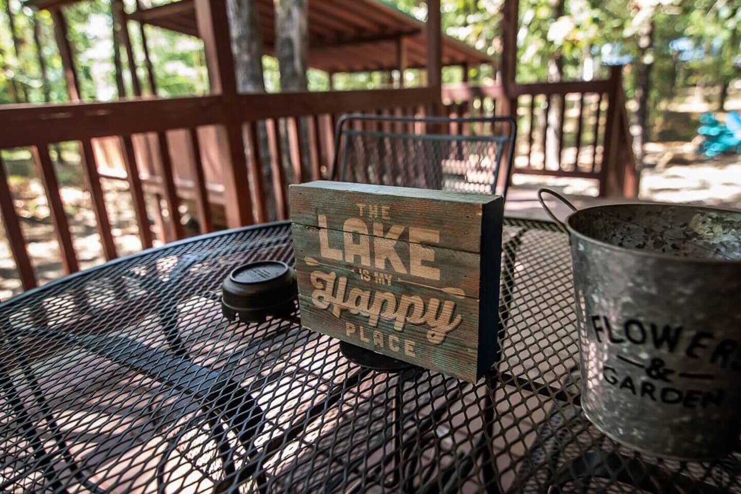 A metal table with a wooden sign that reads "The Lake is my happy place."