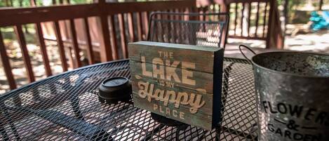 A metal table with a wooden sign that reads "The Lake is my happy place."