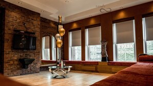 A modern room with a brick wall, a large window with blinds, a round table with a glass top, and a red sofa. - Infinity Apartments Victoria Street (Liverpool)